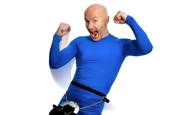 Craig Hill wearing a blue skivvy and blue kilt, laughing with his arms up in the air