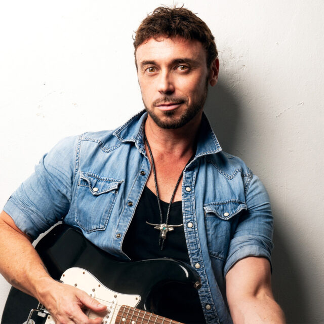 Singer Nathan Foley siting and holding a guitar across his lap