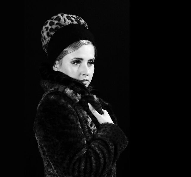 Black and white photo of Rachael Grace wearing a fur coat and hat styled like Barbra Steisand