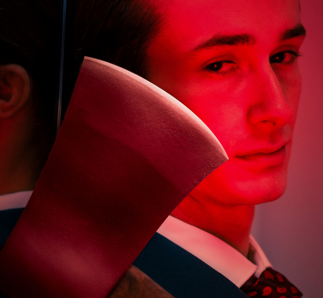 Close head shot of a person in a suit with a large axe resting on their shoulder