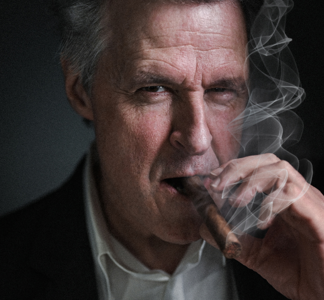 Close up head shot of an actor looking like Bob Hawke smoking a large cigar