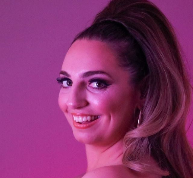Head shot of artist Piera Dennerstein smiling and washed in a pink/red colour