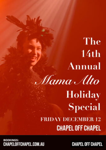 Artist Mama Alto wearing a boa washed in a red light under a spot light