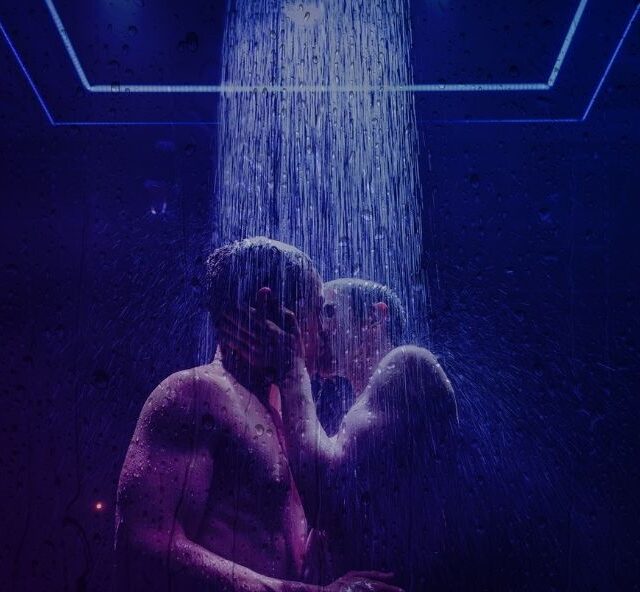 Two naked people kissing under a shower