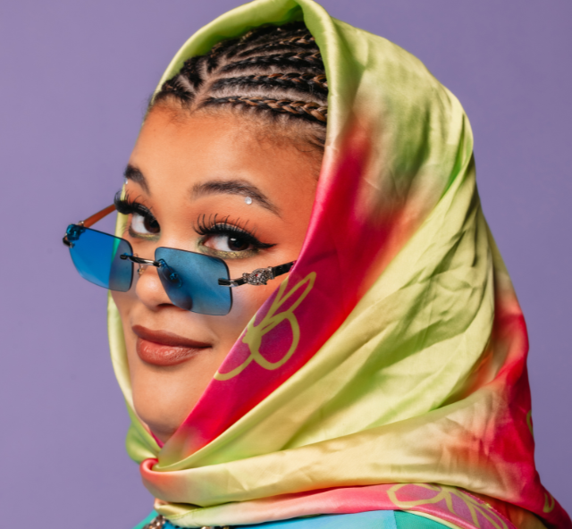 Head shot of Milo Hartill wearing a head scarf and sun glasses