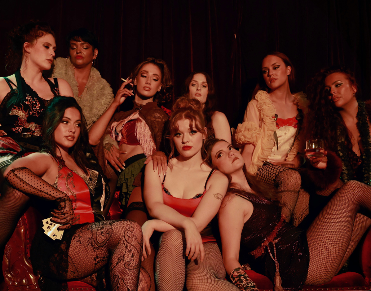 Cast of Sweet Charity sitting around a sofa