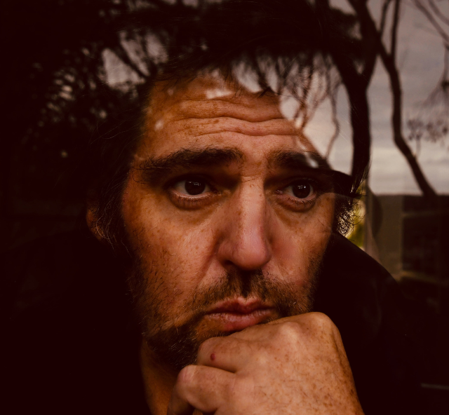 Head shoot of Alex Lloyd with his chin resting on his fist