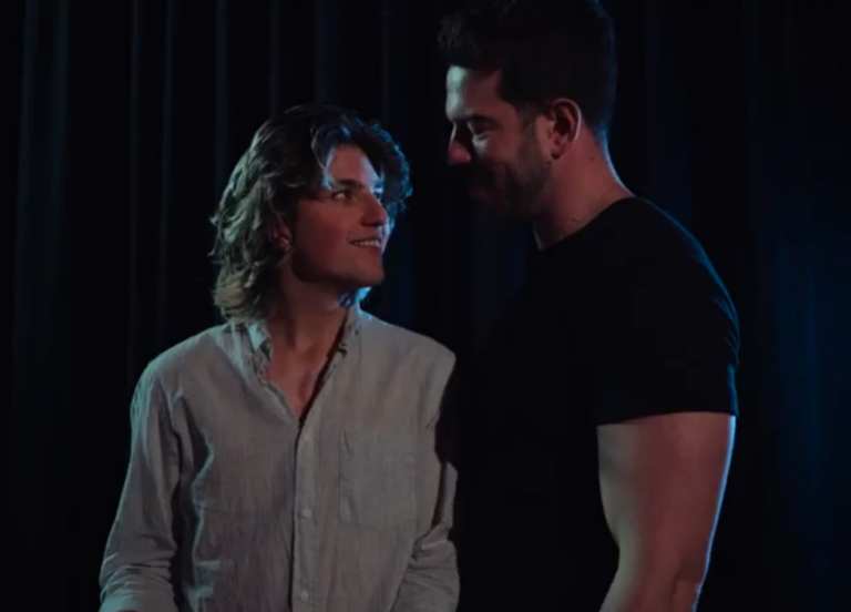 Tall man in a black t-shirt looking at a shorter man in a white short