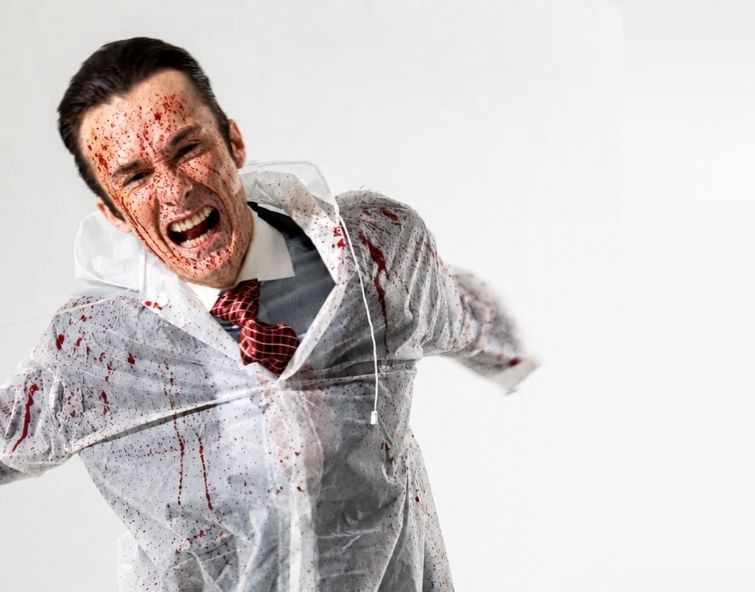 Man in a suit wearing a plastic overcoat splattered with blood and screaming