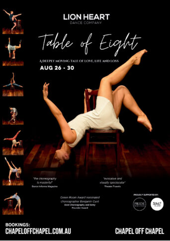 A female dancer wearing a short white sleeveless dress, her torso lies arched backward across the seat of the chair, with her head hanging completely upside down toward the floor.